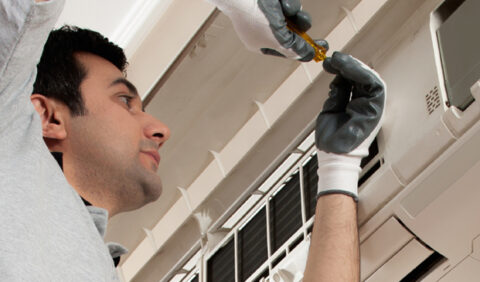Engineer performing maintenance on an air conditioning unit.