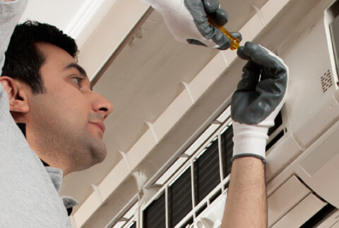Engineer performing maintenance on an air conditioning unit.