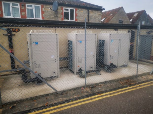 Domestic air conditioning units set up behind homes.